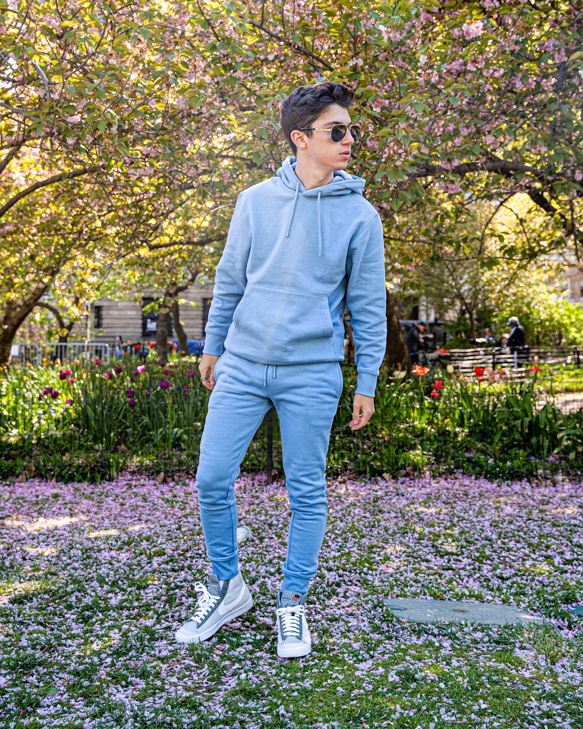 Eitan wears a blue pastel Topman sweatshirt and sweatpants from ASOS and Nike sneakers in a park in NYC.