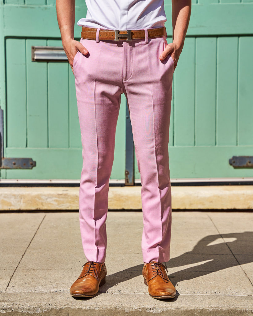 Eitan wears brown menswear Hermes H belt and purple dress pants in front of a green door.